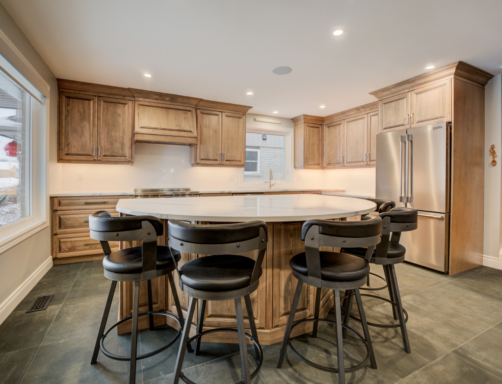 Example of a mid-sized transitional l-shaped eat-in kitchen design in Toronto with an undermount sink, raised-panel cabinets, medium tone wood cabinets, quartz countertops, white backsplash, ceramic backsplash, stainless steel appliances, an island and white countertops