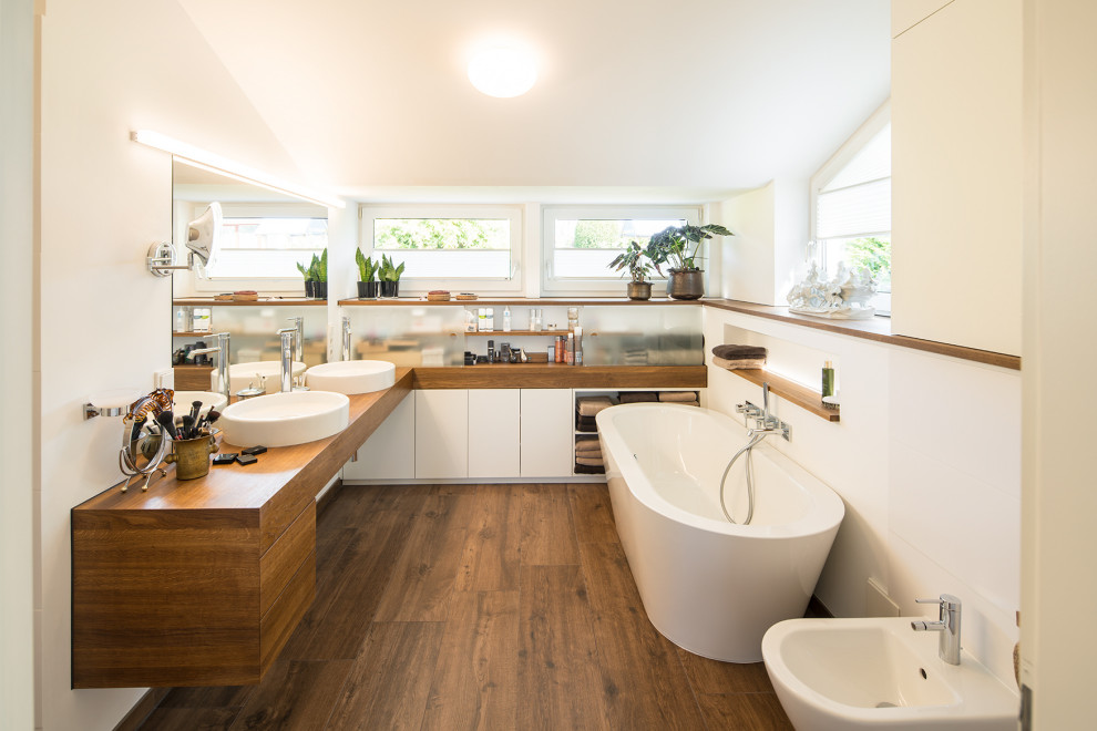 Contemporary master bathroom in Other with flat-panel cabinets, medium wood cabinets, a freestanding tub, white walls, dark hardwood floors, a vessel sink, brown floor, brown benchtops, a double vanity, a floating vanity and vaulted.