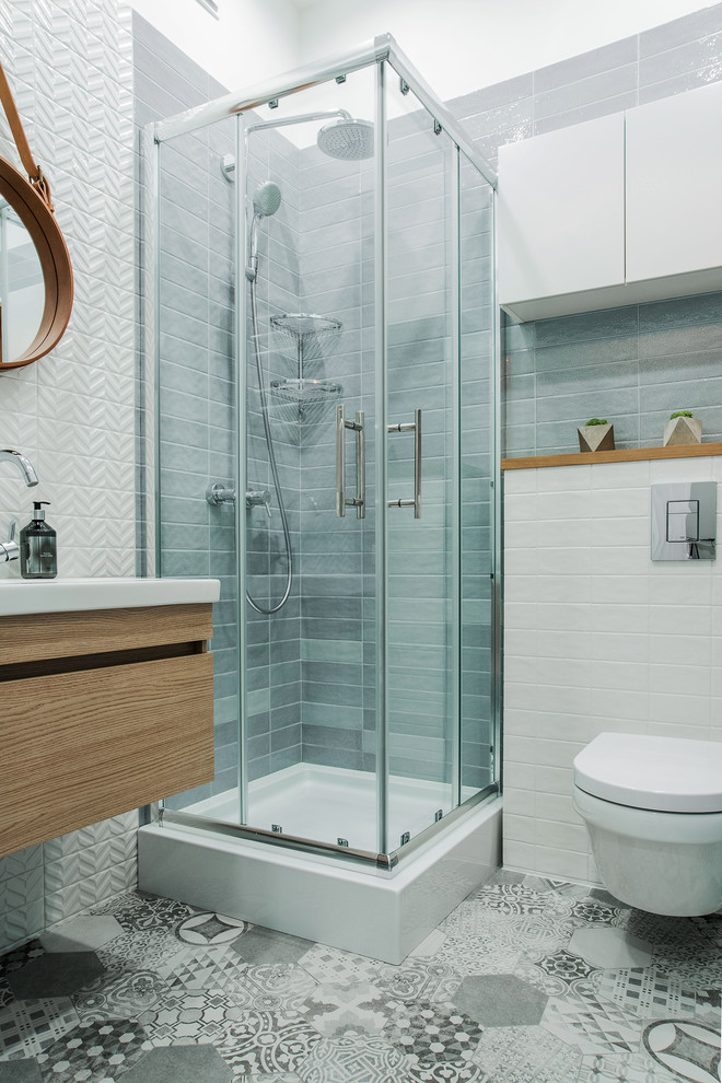 Inspiration for a contemporary 3/4 bathroom in Other with flat-panel cabinets, gray tile, white tile, a sliding shower screen, medium wood cabinets, a corner shower, a wall-mount toilet, grey floor, white walls and a console sink.