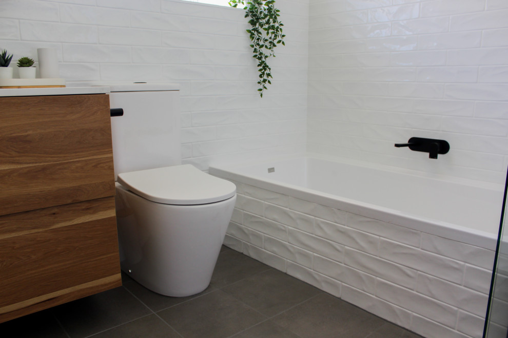 Small modern master bathroom in Perth with flat-panel cabinets, dark wood cabinets, a drop-in tub, a corner shower, a one-piece toilet, white tile, ceramic tile, white walls, porcelain floors, a vessel sink, engineered quartz benchtops, grey floor, a hinged shower door and white benchtops.