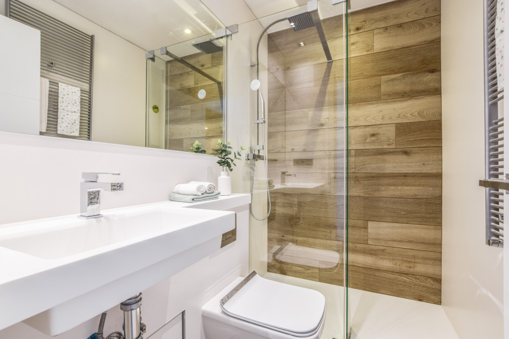 Inredning av ett modernt litet vit vitt badrum med dusch, med vita skåp, våtrum, en vägghängd toalettstol, vit kakel, vita väggar, klinkergolv i porslin, ett väggmonterat handfat, bänkskiva i återvunnet glas, brunt golv och dusch med skjutdörr