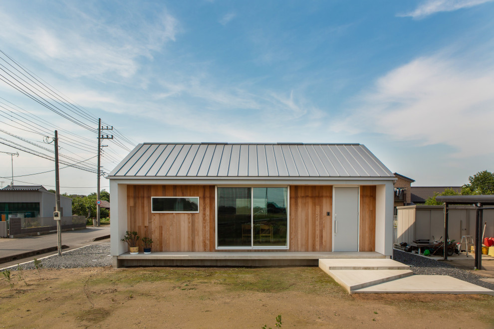 Diseño de fachada de casa gris y gris industrial pequeña de una planta con revestimiento de metal, tejado a dos aguas, tejado de metal y panel y listón