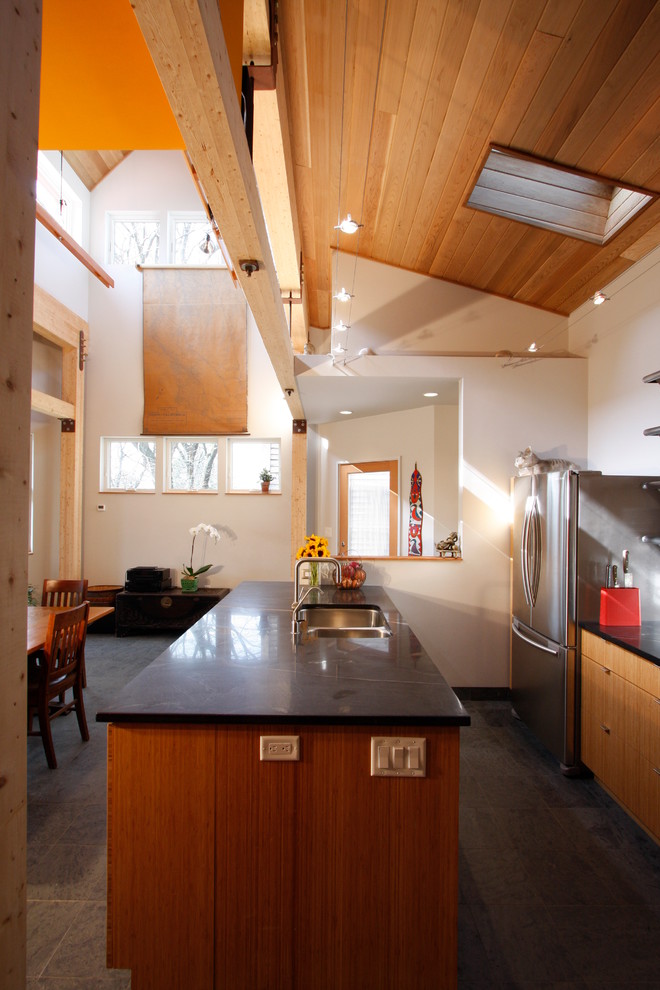 Kitchen - contemporary kitchen idea with an undermount sink, flat-panel cabinets, light wood cabinets, soapstone countertops, white backsplash and stainless steel appliances