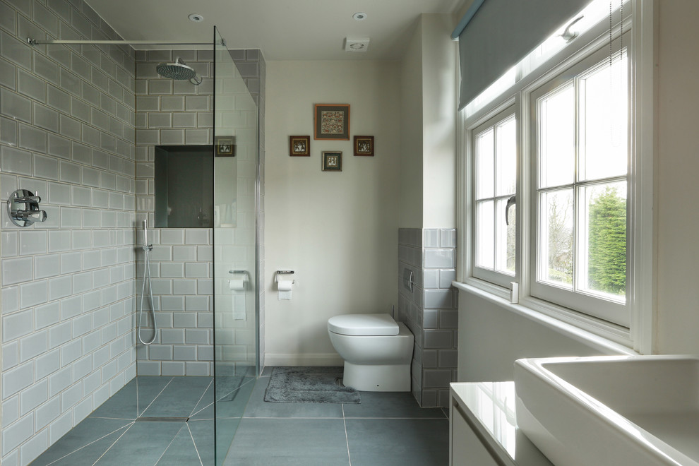 Mid-sized contemporary wet room bathroom in London with flat-panel cabinets, white cabinets, a one-piece toilet, beige walls, a vessel sink, grey floor and an open shower.