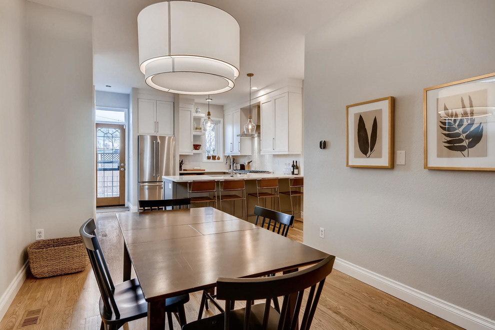 Small transitional u-shaped medium tone wood floor and brown floor kitchen/dining room combo photo in Denver with shaker cabinets, white cabinets, granite countertops, white backsplash, subway tile backsplash, stainless steel appliances, a peninsula and white countertops
