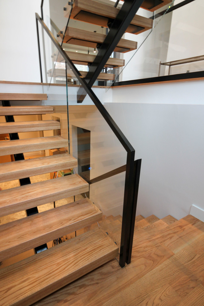 На фото: большая лестница на больцах в стиле модернизм с деревянными ступенями с