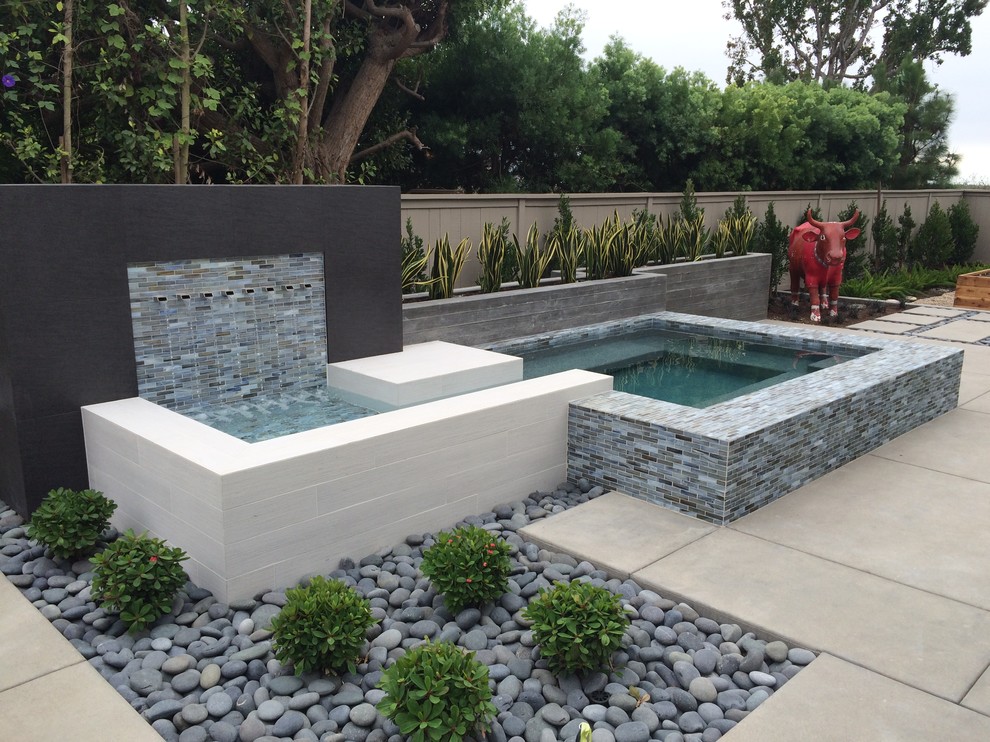 Inspiration for a contemporary backyard custom-shaped pool in Orange County with a water feature and tile.