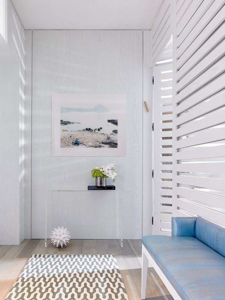 Inspiration for a beach style hallway in Miami with white walls and light hardwood floors.