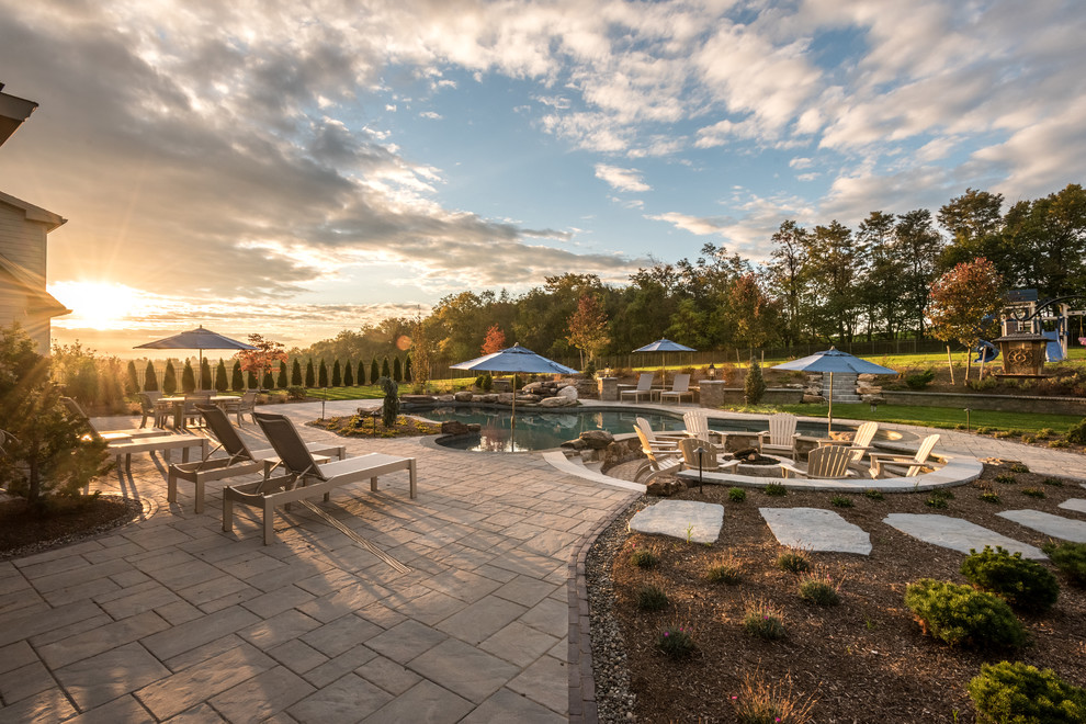 Inspiration for a large transitional backyard concrete paver and custom-shaped pool remodel