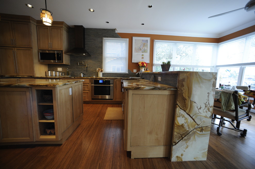 Example of a mid-sized transitional u-shaped light wood floor eat-in kitchen design in Baltimore with a farmhouse sink, light wood cabinets, onyx countertops, stainless steel appliances, an island and beaded inset cabinets