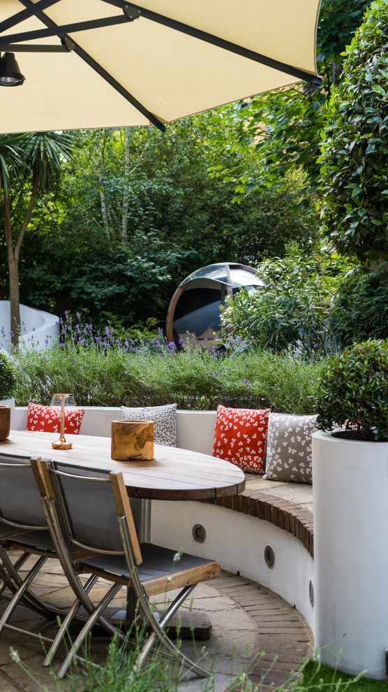 Photo of a medium sized contemporary back patio in London with natural stone paving.