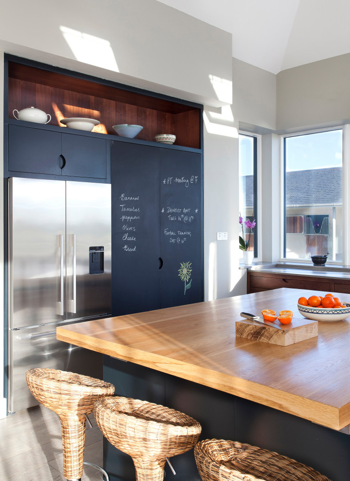Große Moderne Küche in U-Form mit flächenbündigen Schrankfronten, dunklen Holzschränken, Arbeitsplatte aus Holz, Küchenrückwand in Grau, Küchengeräten aus Edelstahl und Kücheninsel in Sonstige