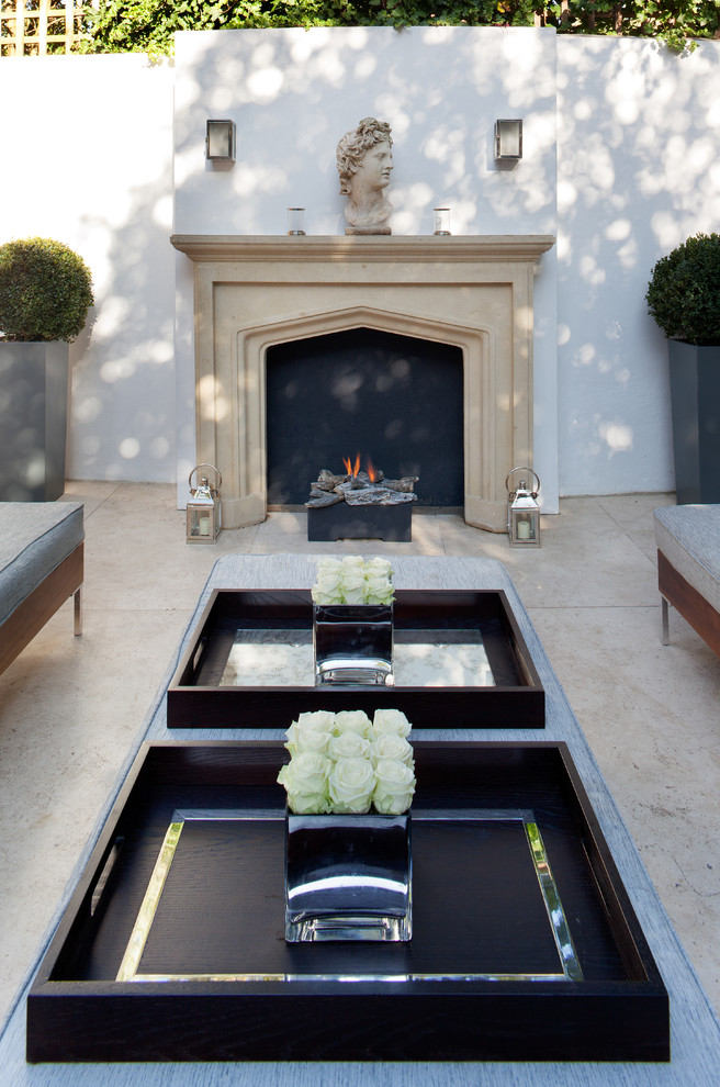 This is an example of a large transitional courtyard patio in London with with fireplace, tile and no cover.