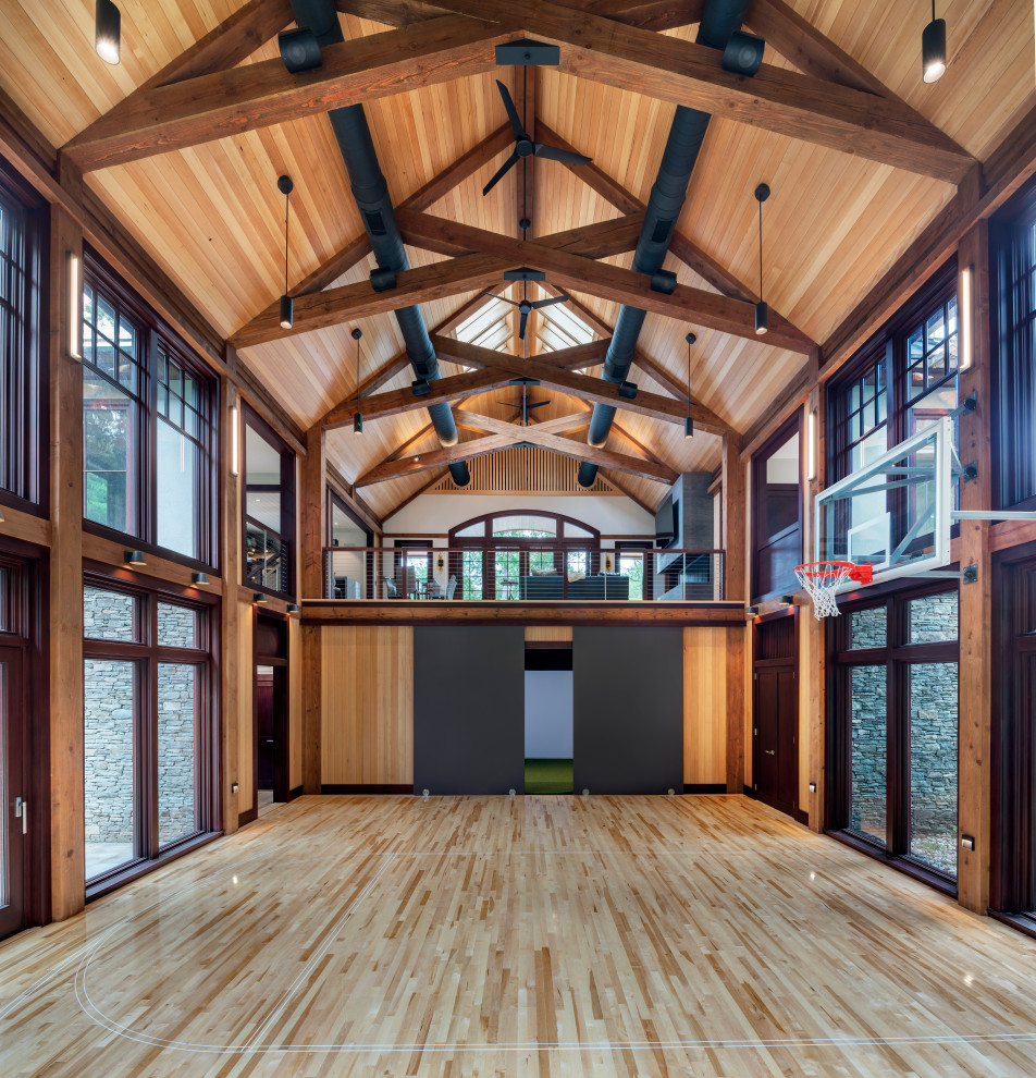 Geräumiger Landhaus Fitnessraum mit Indoor-Sportplatz, brauner Wandfarbe, hellem Holzboden, braunem Boden und freigelegten Dachbalken in Boston