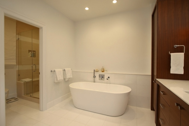 Modernes Badezimmer En Suite mit flächenbündigen Schrankfronten, dunklen Holzschränken, freistehender Badewanne, Duschnische, beigen Fliesen, weißer Wandfarbe und integriertem Waschbecken in Houston