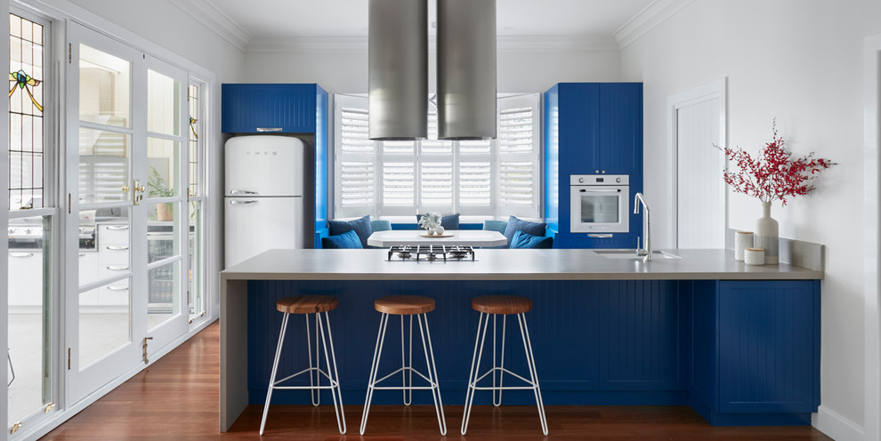 This is an example of a large midcentury single-wall kitchen pantry in Melbourne with a single-bowl sink, beaded inset cabinets, blue cabinets, stainless steel benchtops, stainless steel appliances, medium hardwood floors and with island.