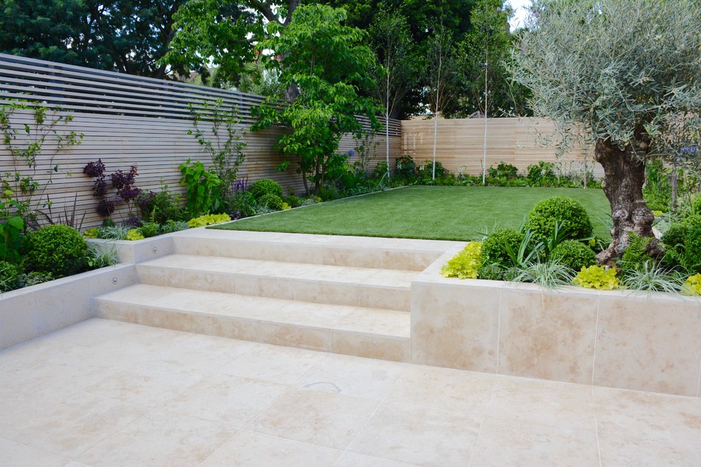 This is an example of a medium sized contemporary back full sun garden for summer in London with natural stone paving.