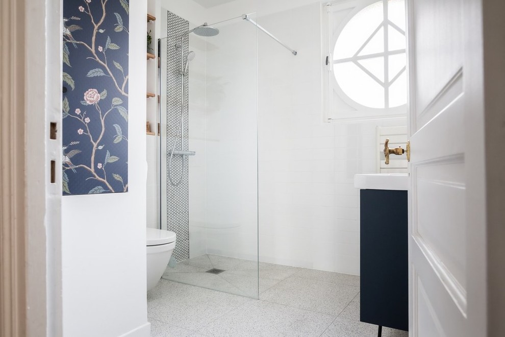 Photo of a small contemporary 3/4 bathroom in Paris with flat-panel cabinets, blue cabinets, a curbless shower, a wall-mount toilet, white tile, ceramic tile, white walls, terrazzo floors, an integrated sink, grey floor and white benchtops.