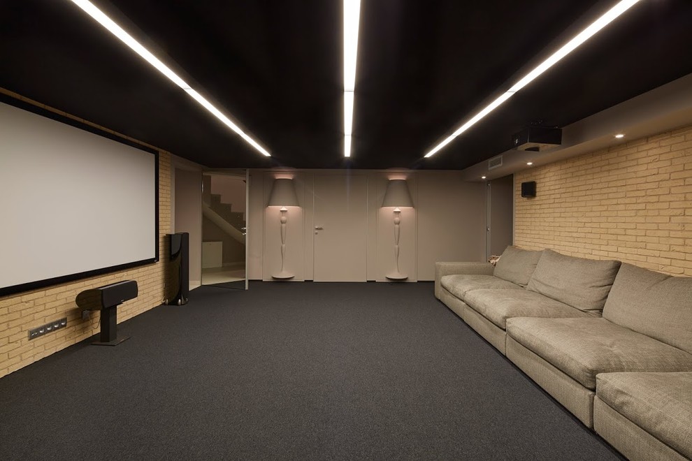 This is an example of a contemporary enclosed home theatre in Moscow with beige walls, carpet, a projector screen and grey floor.