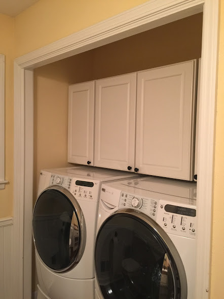 This is an example of a small traditional single-wall laundry cupboard in Orange County with raised-panel cabinets, white cabinets, a side-by-side washer and dryer and beige walls.