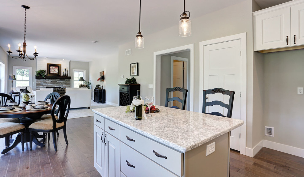 Photo of a mid-sized country l-shaped eat-in kitchen in Other with a double-bowl sink, white cabinets, quartz benchtops, white splashback, subway tile splashback, stainless steel appliances, medium hardwood floors, with island and beige benchtop.