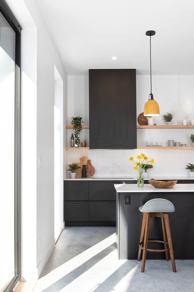 Mid-sized beach style kitchen in Other with flat-panel cabinets, black cabinets, recycled glass benchtops, white splashback, ceramic splashback, panelled appliances, ceramic floors, with island, grey floor and white benchtop.