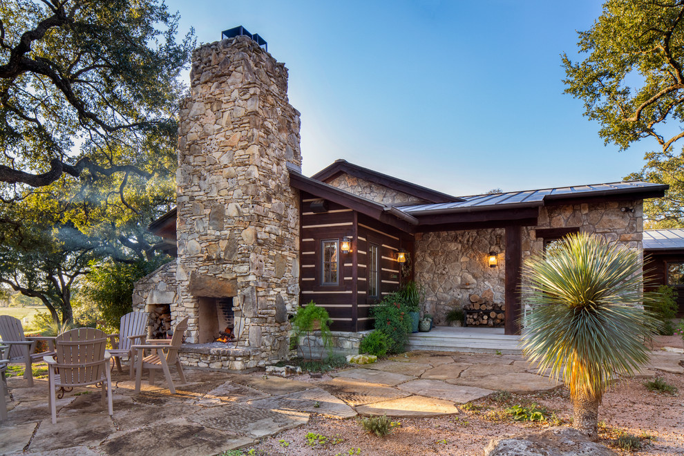 Inspiration for a country side yard patio in Austin with with fireplace, natural stone pavers and no cover.