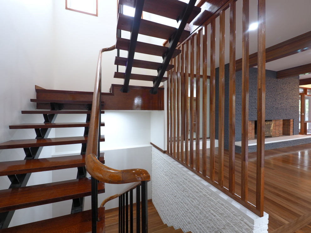 Photo of a mid-sized midcentury wood u-shaped staircase in Brisbane with open risers and wood railing.