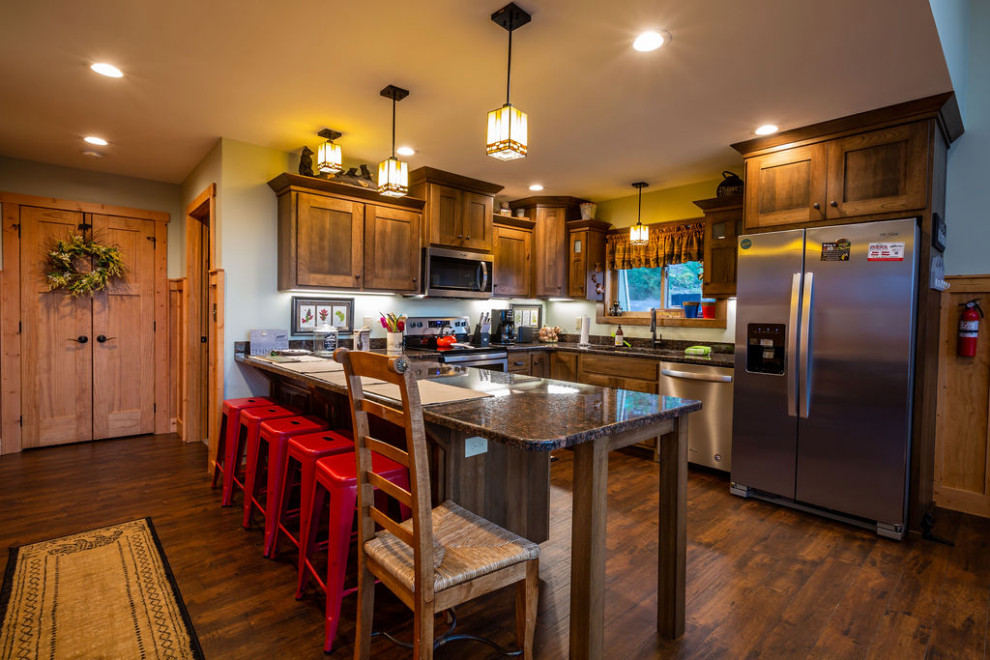 Mid-sized mountain style u-shaped vinyl floor and brown floor open concept kitchen photo with shaker cabinets, brown cabinets, granite countertops, gray backsplash, a peninsula and gray countertops