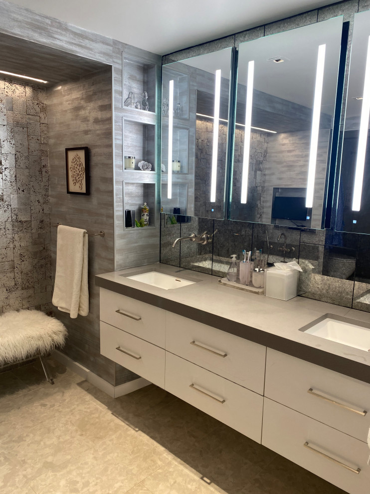 This is an example of a large contemporary master bathroom in New York with flat-panel cabinets, white cabinets, a freestanding tub, gray tile, glass tile, concrete benchtops, grey benchtops, a double vanity, a floating vanity, an undermount sink, a one-piece toilet, white walls, porcelain floors, beige floor, wallpaper, an alcove shower and a hinged shower door.