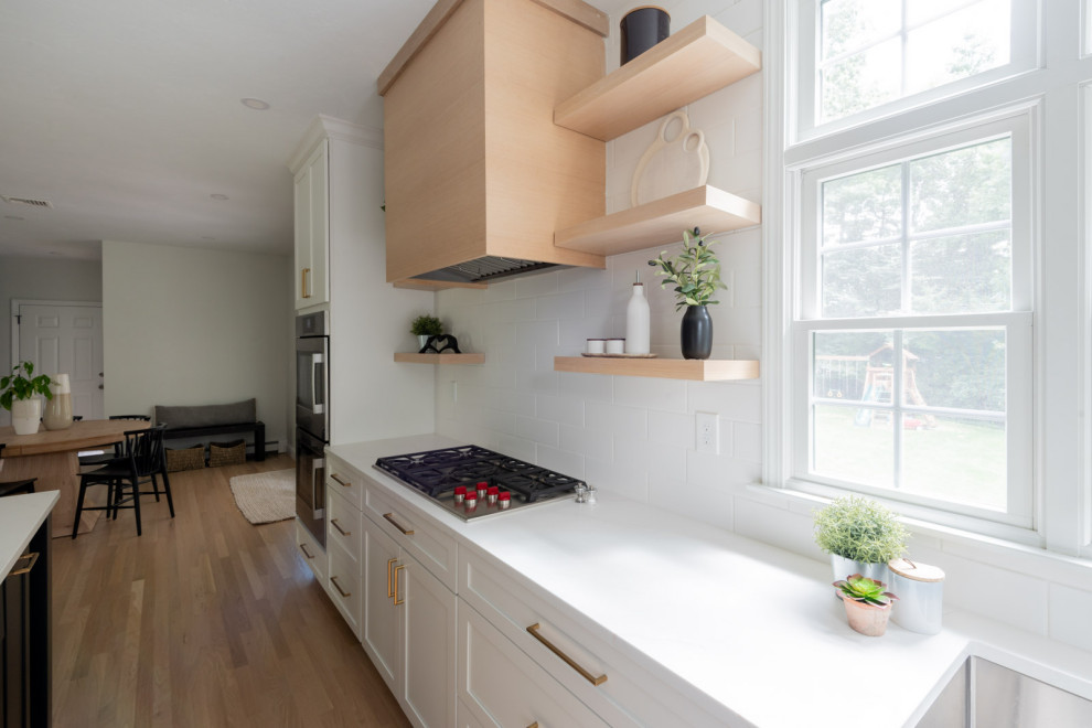 Huge transitional u-shaped light wood floor and beige floor eat-in kitchen photo in Boston with an undermount sink, shaker cabinets, white cabinets, quartz countertops, white backsplash, subway tile backsplash, stainless steel appliances, an island and white countertops