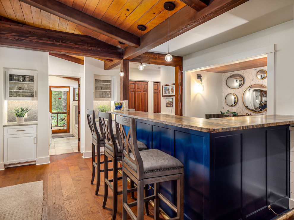 This is an example of a mid-sized country l-shaped seated home bar in Other with recessed-panel cabinets, white cabinets, quartzite benchtops, vinyl floors, brown floor and brown benchtop.