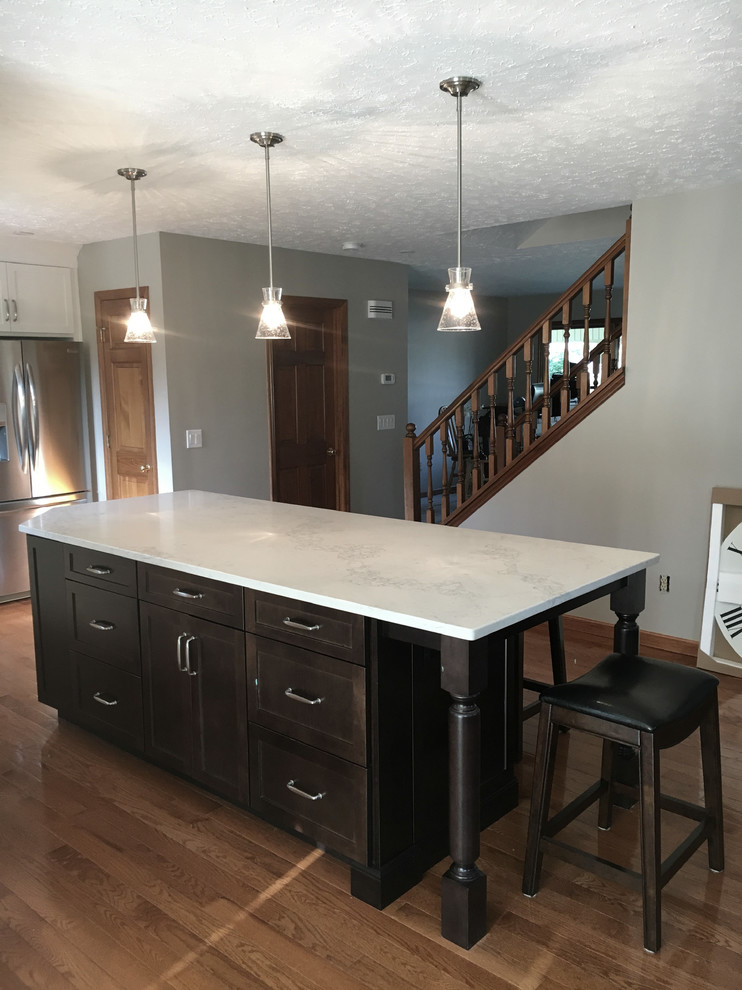 Example of a large transitional single-wall medium tone wood floor eat-in kitchen design with an undermount sink, shaker cabinets, white cabinets, granite countertops, multicolored backsplash, marble backsplash, stainless steel appliances, an island and black countertops