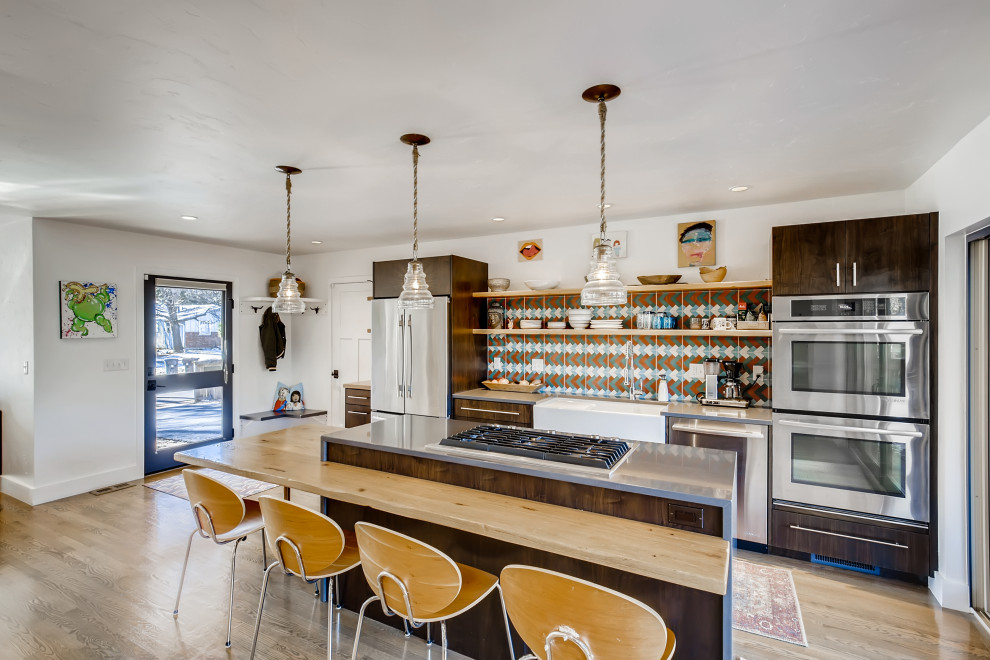 This is an example of a mid-sized contemporary single-wall eat-in kitchen in Denver with a farmhouse sink, flat-panel cabinets, dark wood cabinets, quartz benchtops, multi-coloured splashback, cement tile splashback, stainless steel appliances, light hardwood floors, with island, beige floor and grey benchtop.