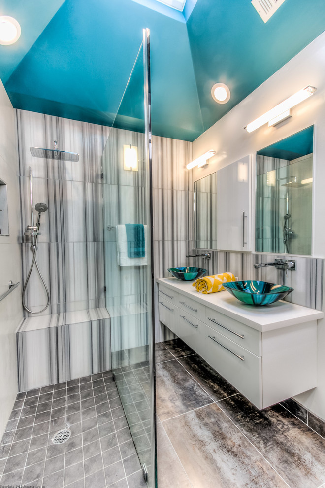 Photo of a mid-sized contemporary 3/4 bathroom in San Francisco with a vessel sink, flat-panel cabinets, white cabinets, an open shower, gray tile, stone tile, white walls, stainless steel benchtops, multi-coloured floor, an open shower and white benchtops.