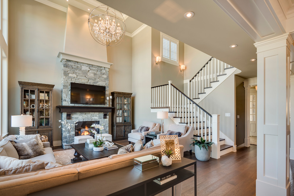 This is an example of a mid-sized traditional open concept living room in Vancouver with beige walls, medium hardwood floors, a standard fireplace, a stone fireplace surround and a wall-mounted tv.