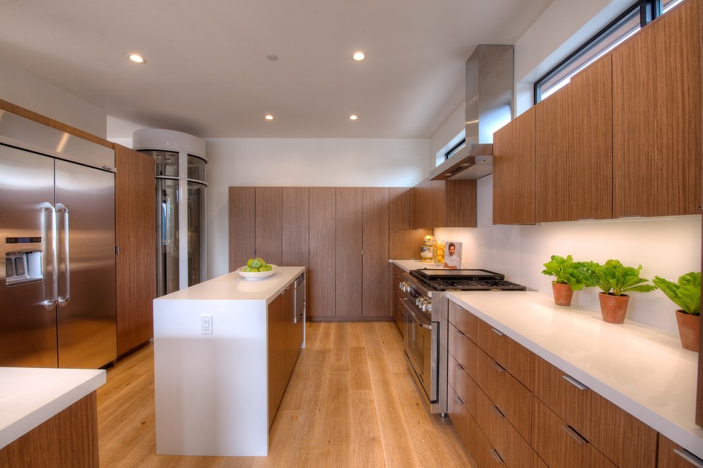 Photo of a mid-sized contemporary u-shaped eat-in kitchen in San Francisco with light wood cabinets, white splashback, stainless steel appliances, with island and light hardwood floors.