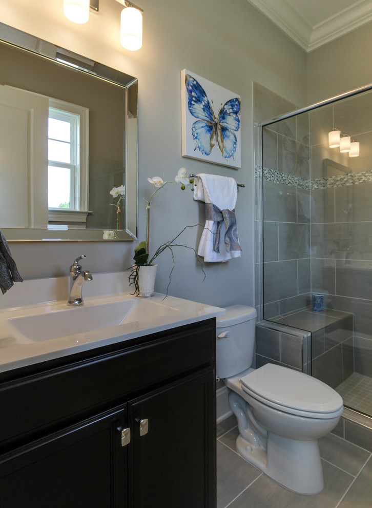This is an example of a small transitional 3/4 bathroom in Raleigh with recessed-panel cabinets, dark wood cabinets, a two-piece toilet, beige tile, ceramic tile, ceramic floors, an undermount sink and marble benchtops.