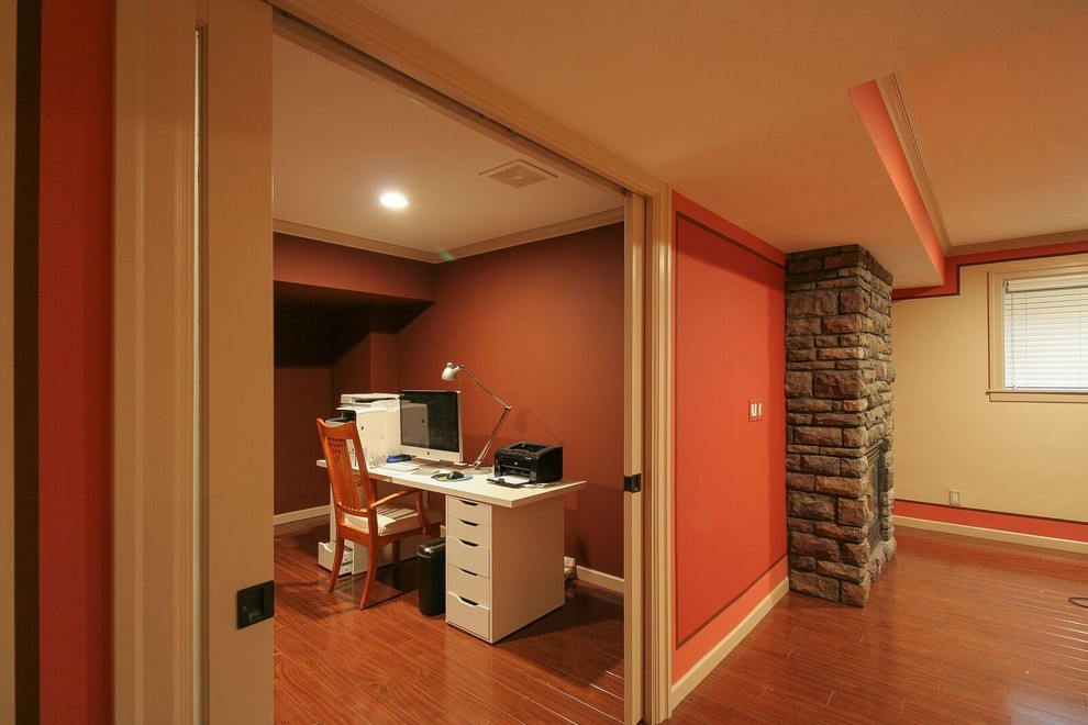 Inspiration for a mid-sized transitional underground medium tone wood floor and brown floor basement remodel in Vancouver with orange walls, a standard fireplace and a stone fireplace