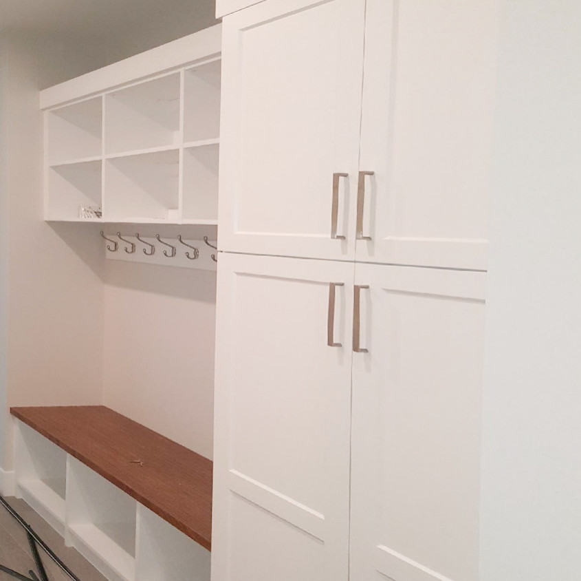 Example of a transitional light wood floor and beige floor mudroom design with gray walls and a white front door