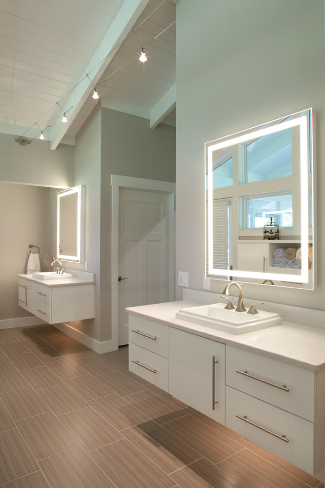 This is an example of a contemporary bathroom in Cincinnati with a drop-in sink, flat-panel cabinets, white cabinets, engineered quartz benchtops, porcelain tile, grey walls, porcelain floors and brown tile.