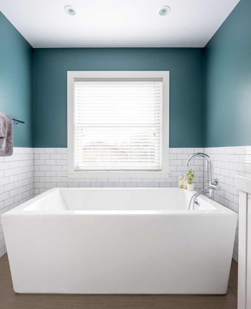 This is an example of a small arts and crafts master bathroom in Seattle with white cabinets, a freestanding tub, a corner shower, white tile, porcelain tile, porcelain floors, a sliding shower screen, a single vanity and a freestanding vanity.