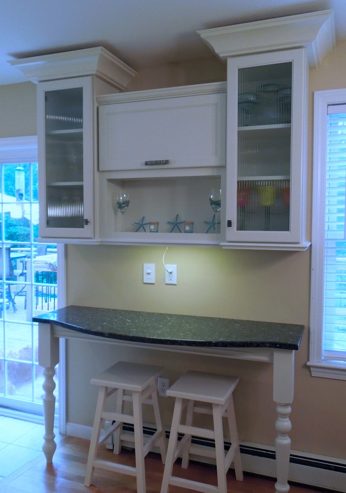 This is an example of a mid-sized beach style u-shaped open plan kitchen in Charleston with an undermount sink, recessed-panel cabinets, white cabinets, recycled glass benchtops, glass tile splashback, stainless steel appliances, ceramic floors, with island and green splashback.