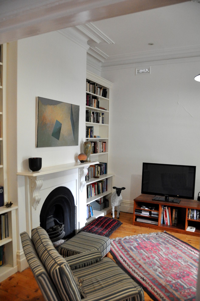 Inspiration for a mid-sized traditional open concept living room in Melbourne with a library, white walls, medium hardwood floors, a standard fireplace and a plaster fireplace surround.