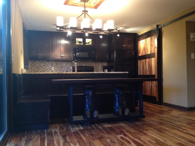 Inspiration for a small rustic galley medium tone wood floor and brown floor eat-in kitchen remodel with an undermount sink, shaker cabinets, dark wood cabinets, granite countertops, brown backsplash, glass tile backsplash, black appliances and a peninsula