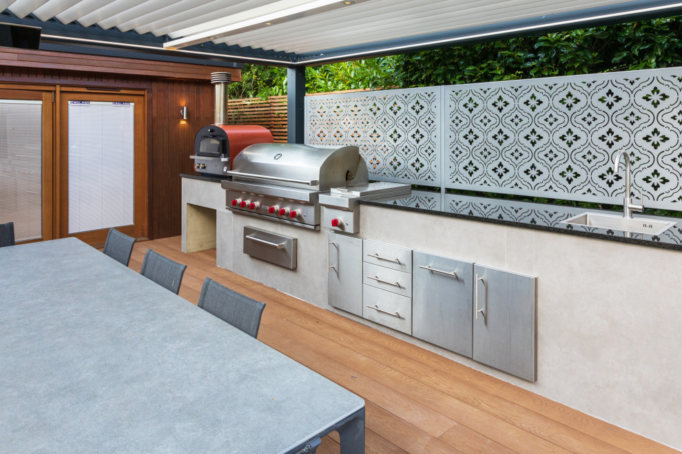 На фото: пергола на террасе среднего размера на заднем дворе в современном стиле с летней кухней и зоной барбекю с