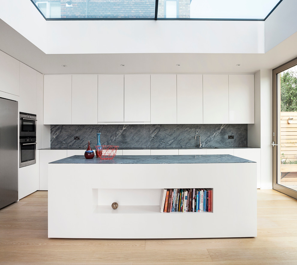 Inspiration for a large modern l-shaped open plan kitchen in London with white cabinets, marble benchtops, grey splashback, stone slab splashback, stainless steel appliances, light hardwood floors, with island, an undermount sink and flat-panel cabinets.