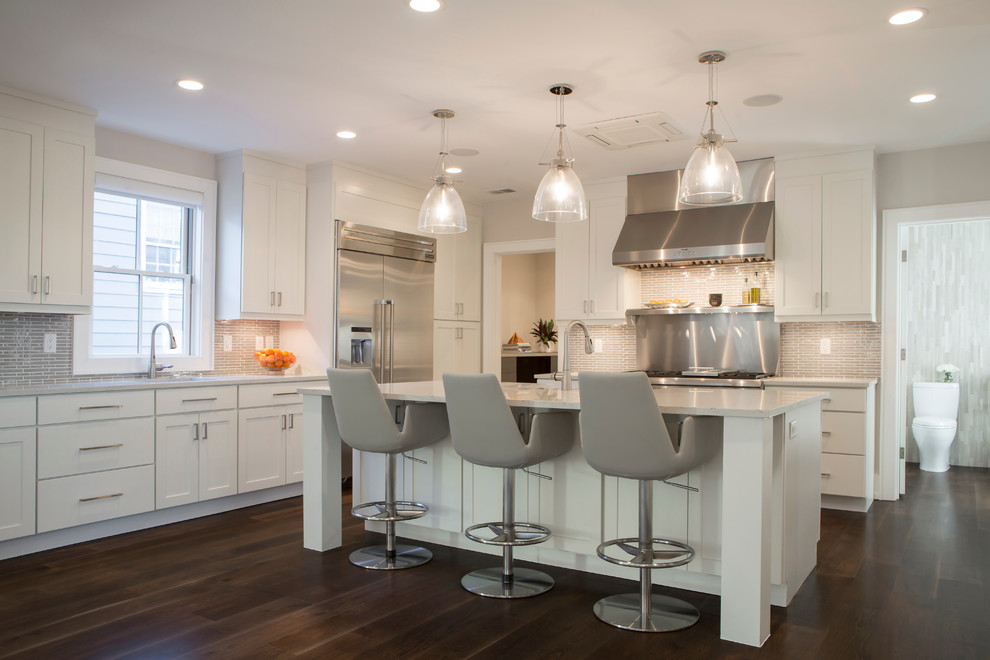 Photo of a transitional l-shaped kitchen in Charleston with shaker cabinets, white cabinets, grey splashback, matchstick tile splashback, stainless steel appliances, dark hardwood floors and with island.