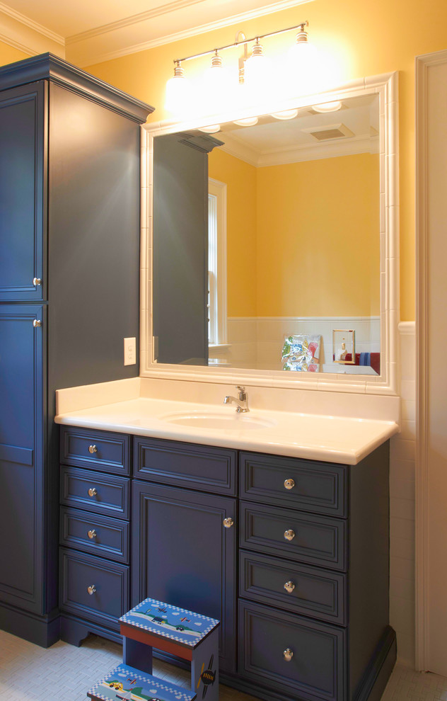 Mid-sized transitional kids' bathroom photo with recessed-panel cabinets, blue cabinets, yellow walls and an undermount sink