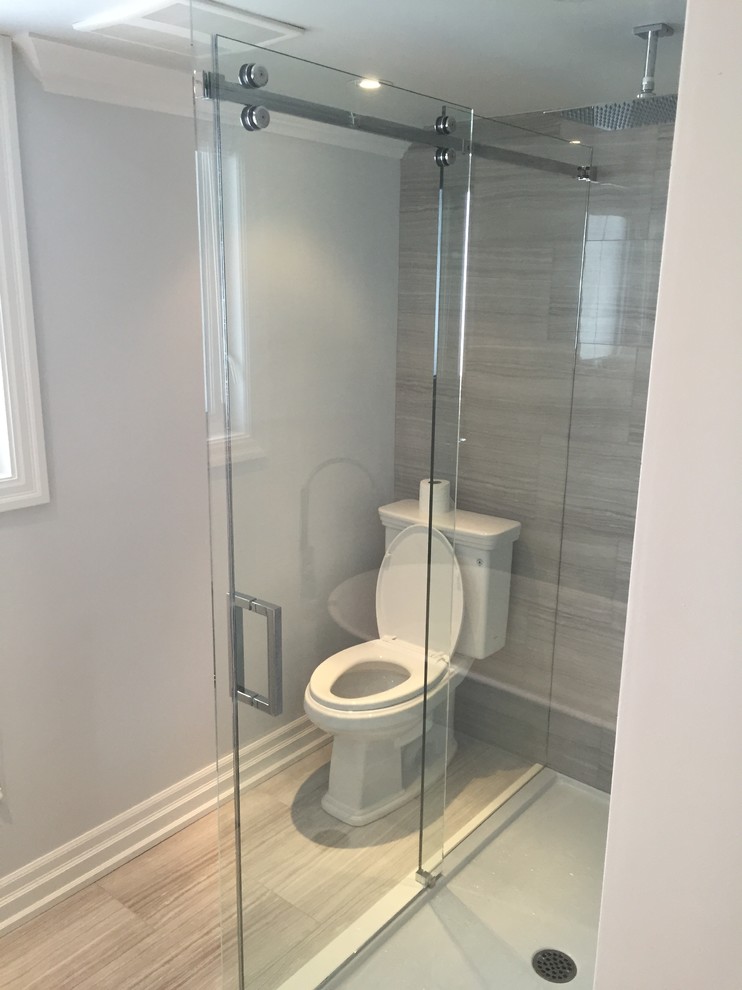 Photo of a mid-sized contemporary 3/4 bathroom in Toronto with shaker cabinets, white cabinets, a freestanding tub, a corner shower, a two-piece toilet, gray tile, ceramic tile, grey walls, ceramic floors, an undermount sink, granite benchtops, grey floor and a hinged shower door.